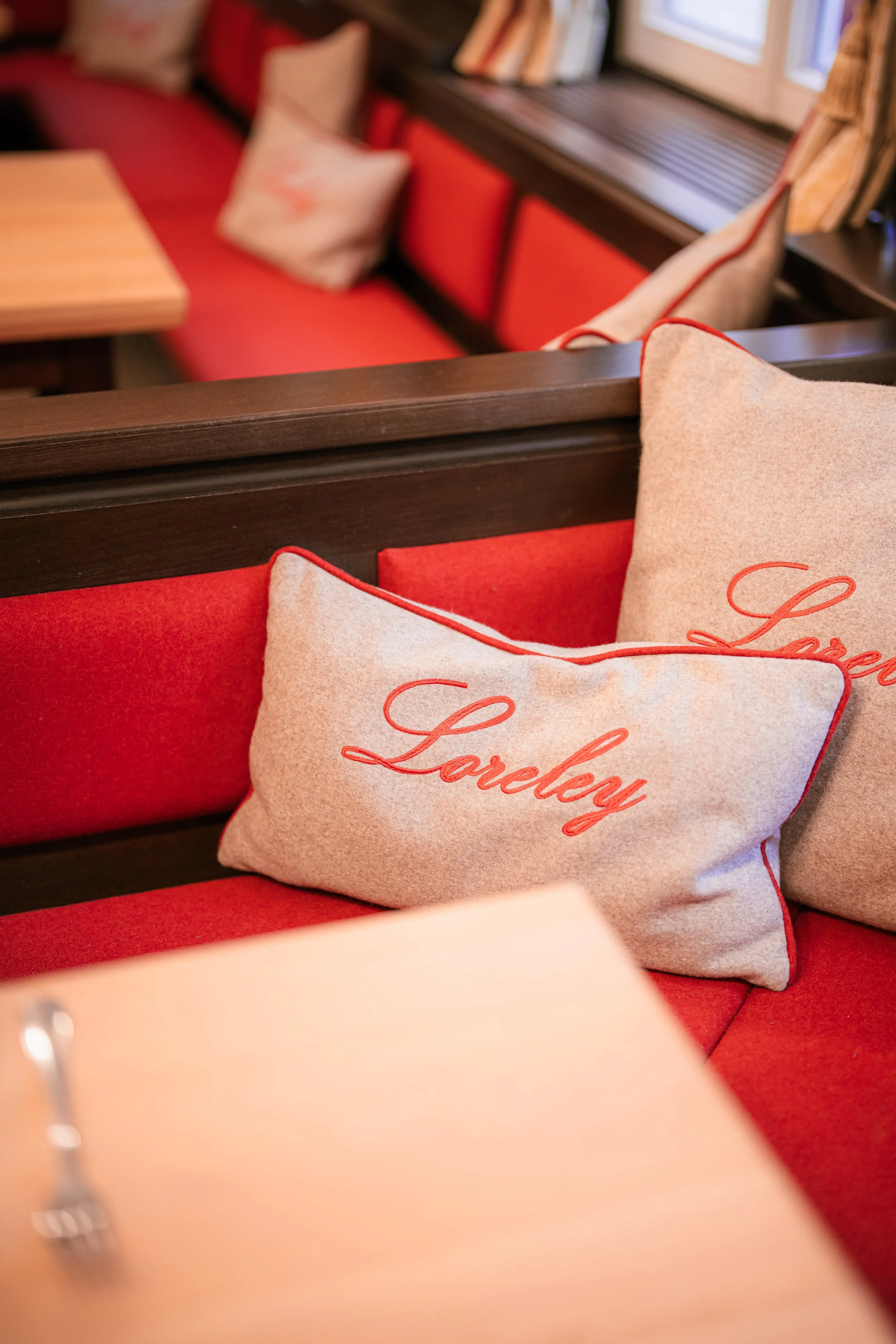 Rote Sitzbänke mit „Loreley"-Stickerei und gedecktem Holztisch