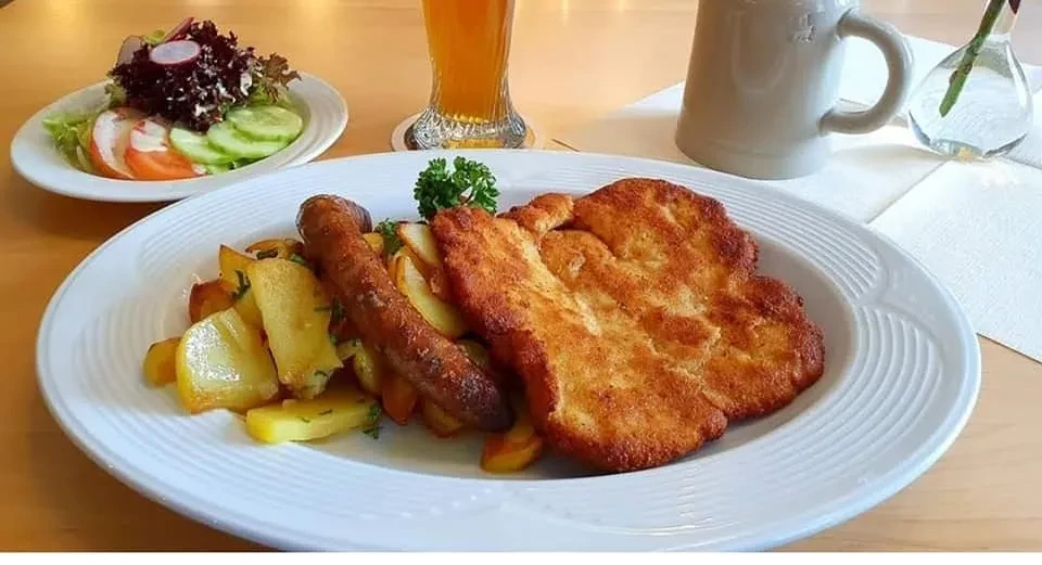 Knuspriges Schnitzel mit Bratwürsten, Bratkartoffeln und Salat